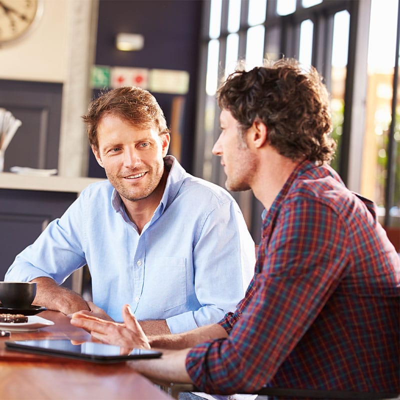 2 white men having a conversation over a coffee