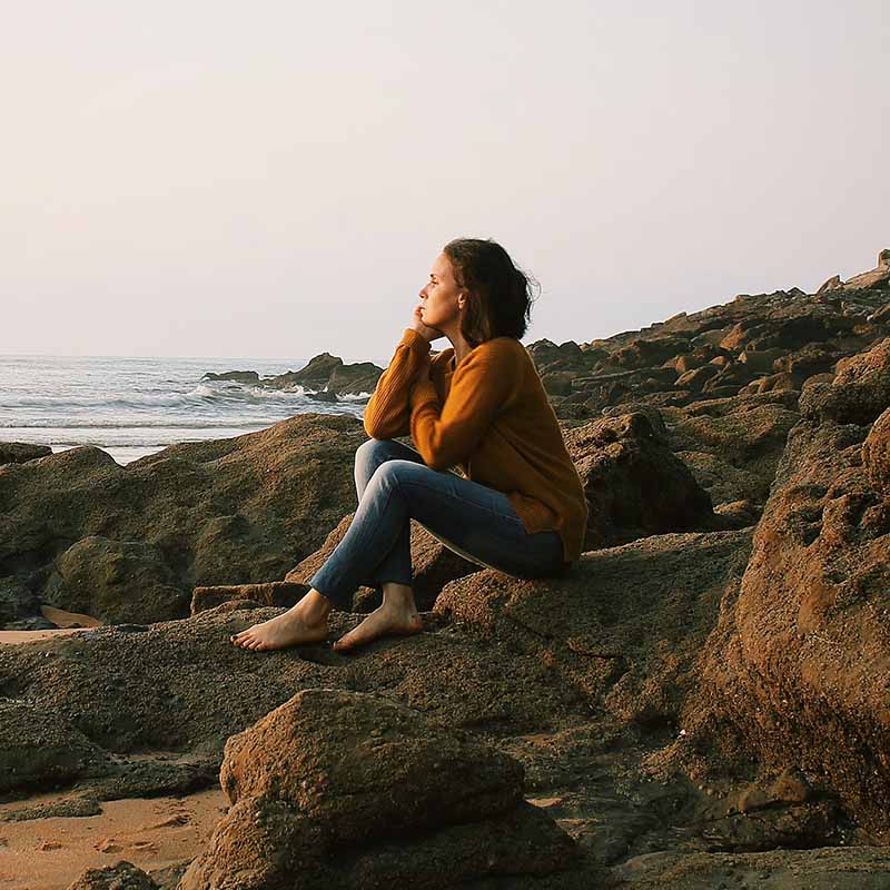 An image of a woman on the beach who think the positivity in the surroundings